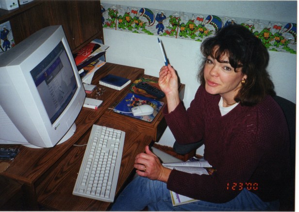 Mom pecking away at the computer with Ninja Turtle wallpaper.