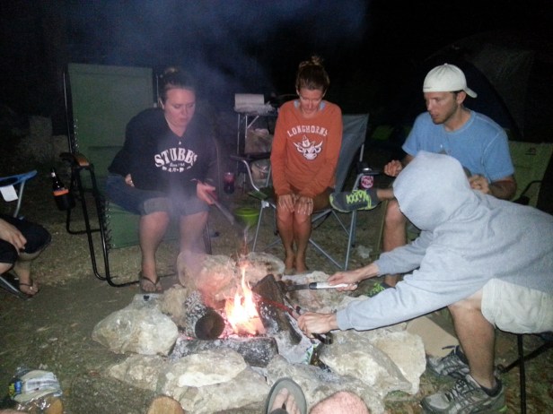 The gang keeps warm over a roaring campfire.