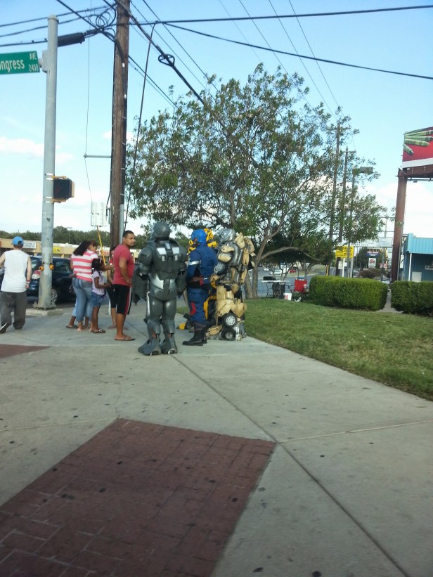 Some random robotic super heroes standing on a street corner for an apparent reason.