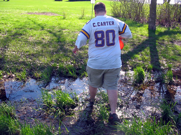 Jason wading through murky water while playing frisbee golf.