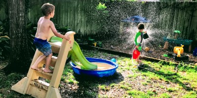 kids playing kiddie pool summer fun splashing sprinkler water