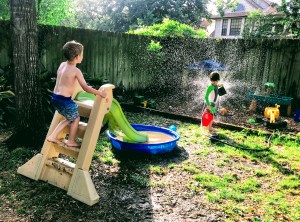 kids playing kiddie pool summer fun splashing sprinkler water